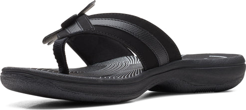 A black sandal with a thong-style toe post and a decorative flower on the strap.
