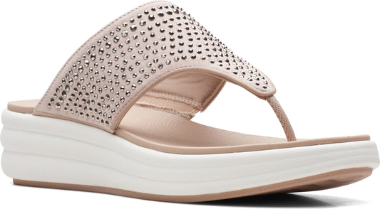 Sandal with light tan thong strap and wide band adorned with metallic studs on a white platform sole.