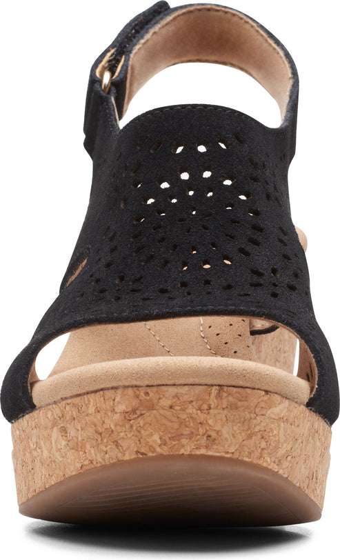 Front view of black wedge sandal with decorative cutouts and cork platform.
