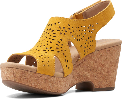 A yellow wedge sandal with laser-cut details and an ankle strap.