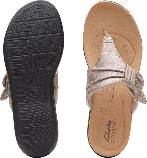 Pair of flat sandals, one showing the black sole with wave pattern, the other showing beige insole, and toe post with a bow.