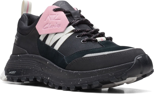 A black trail running shoe with a lug sole, suede and nylon upper, white elastic straps and a pink logo tag.