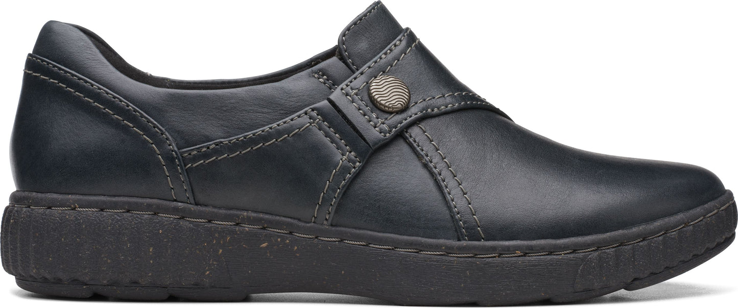 A black slip-on shoe with decorative stitching and a button detail.