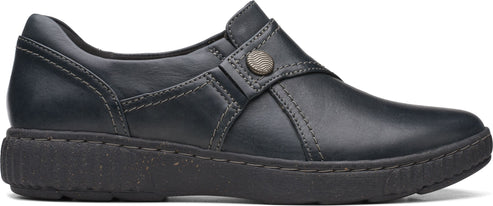 A black slip-on shoe with decorative stitching and a button detail.
