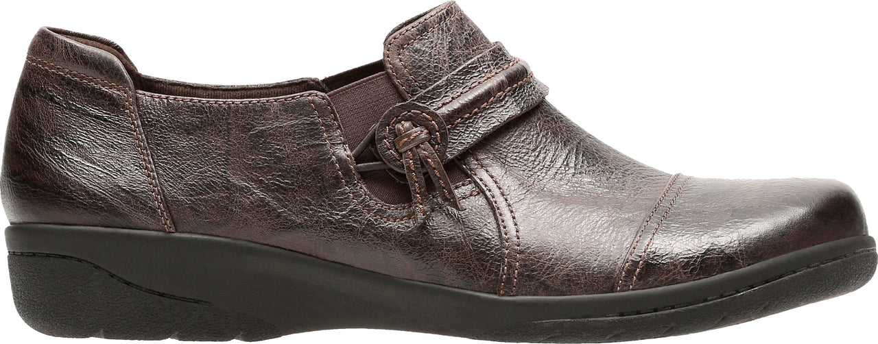 A bronze-colored loafer with a decorative strap and knotted button detail.