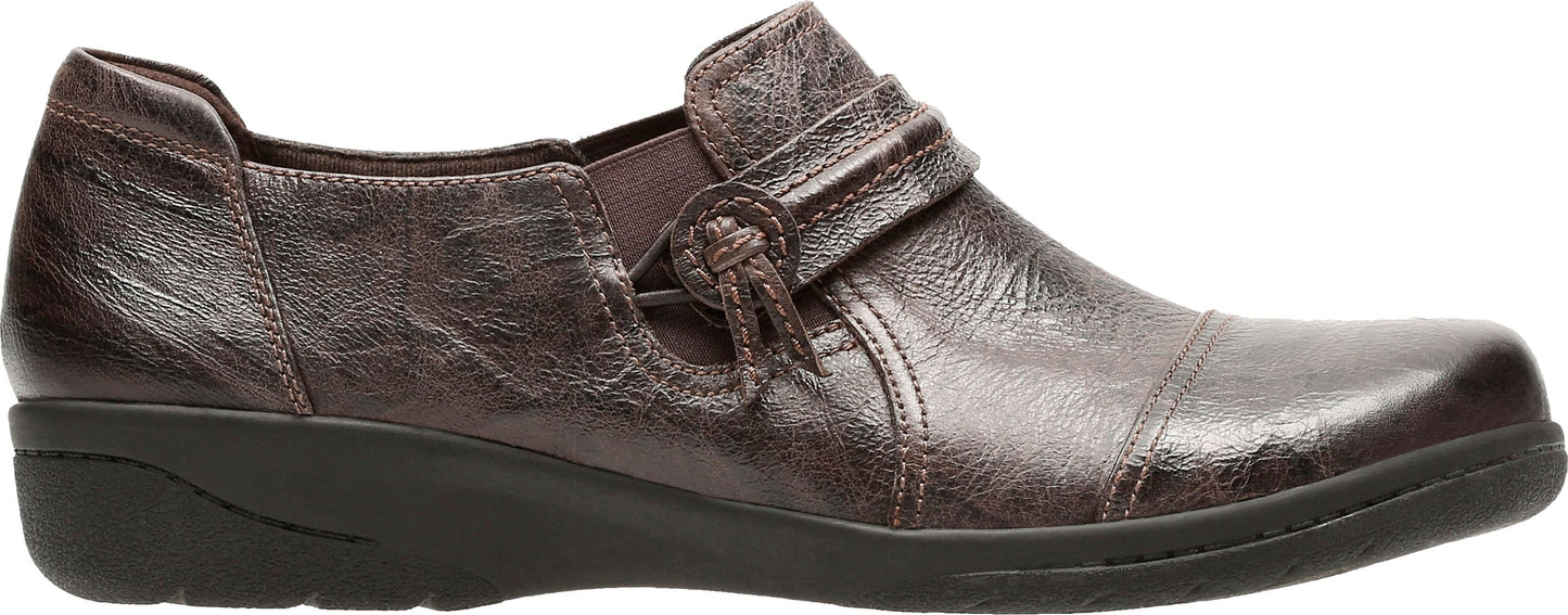 A bronze-colored loafer with a decorative strap and knotted button detail.