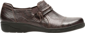 A bronze-colored loafer with a decorative strap and knotted button detail.