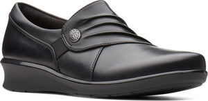 Black, rounded-toe, slip-on shoe with a low wedge heel and decorative button.