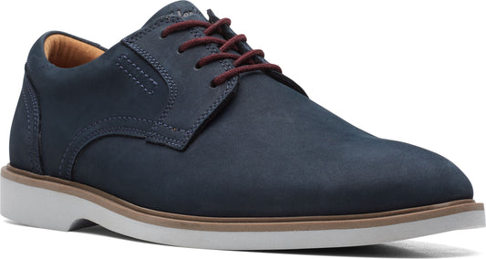 Close-up of a navy dress shoe with red laces, tan interior, brown welt, and white sole.