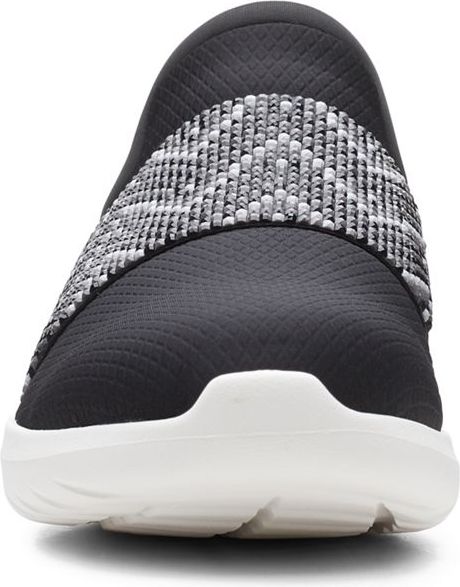 Front view of a black slip-on sneaker with a white sole and a gray and white patterned elastic strap.