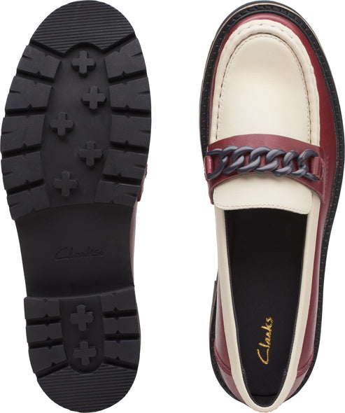 Pair of shoes, viewed from the sole and top. One is a lug-soled black outsole. The other is a red and cream colored loafer with a decorative chain.
