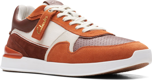 A low-top sneaker with orange, brown, and white paneling and off-white laces and sole. The name 'Clarks' is on a tag.