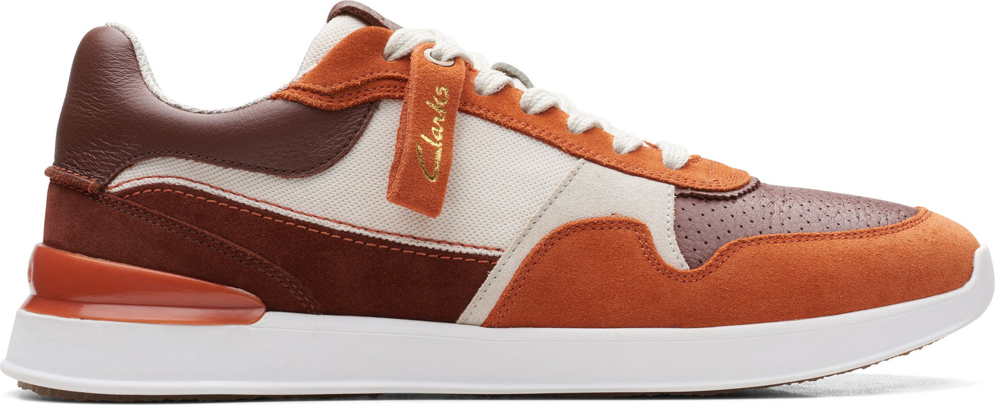 A low-rise sneaker featuring panels in brown, orange and beige with white laces and sole.