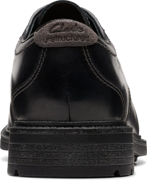 Back view of a black leather shoe with dark gray "Clarks Unstructured" label.