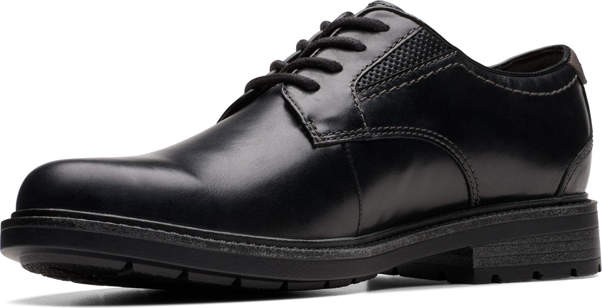 Black leather dress shoe with laces and textured detailing near the heel.