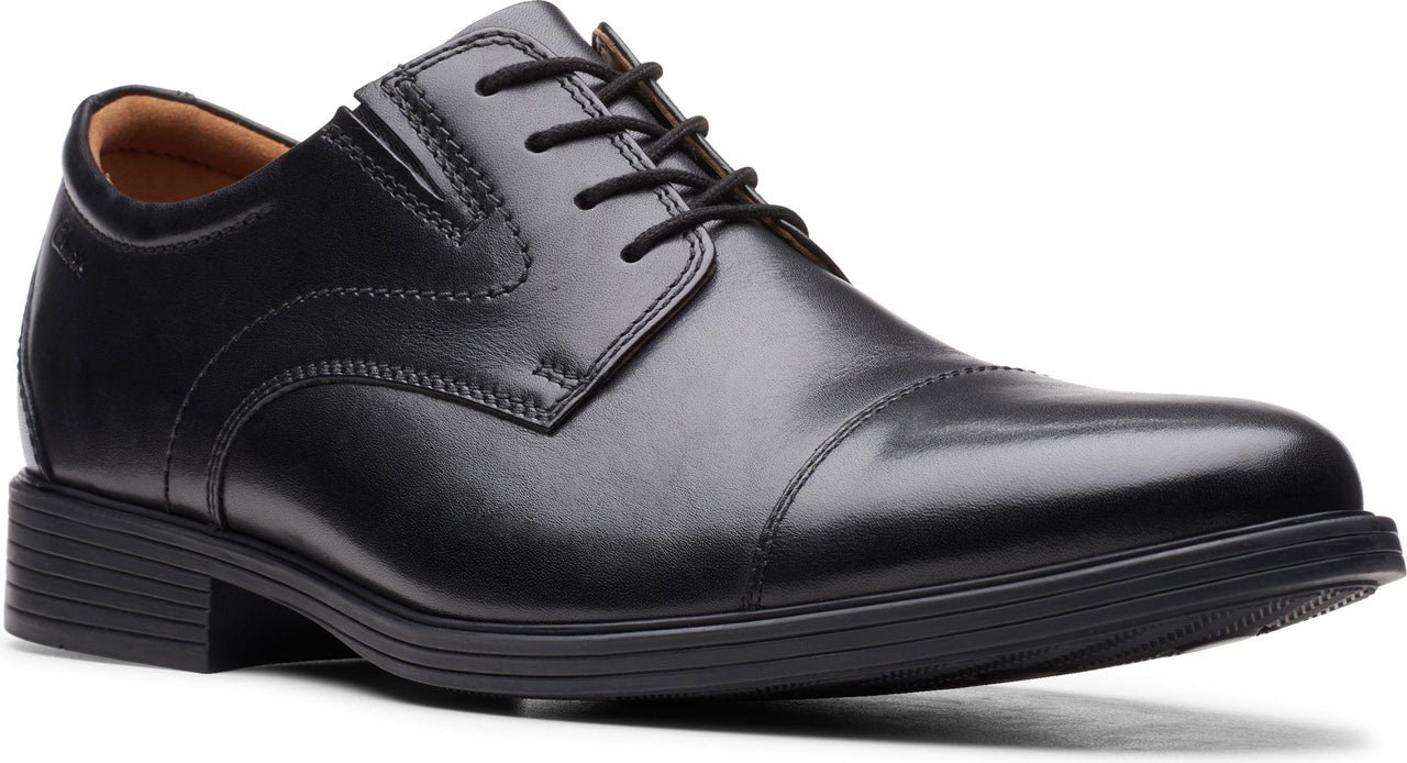 A black, cap-toe dress shoe with a lace-up closure and a slight heel.