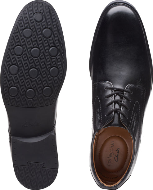 Pair of black leather dress shoes, one showing the sole with circular treads and the other showing the laces and insole.