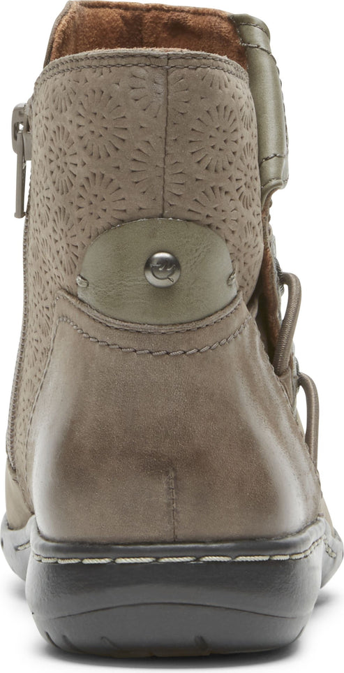A tan, ankle-high boot with a decorative, laser-cut design on the upper shaft, a side zipper, and a dark sole.