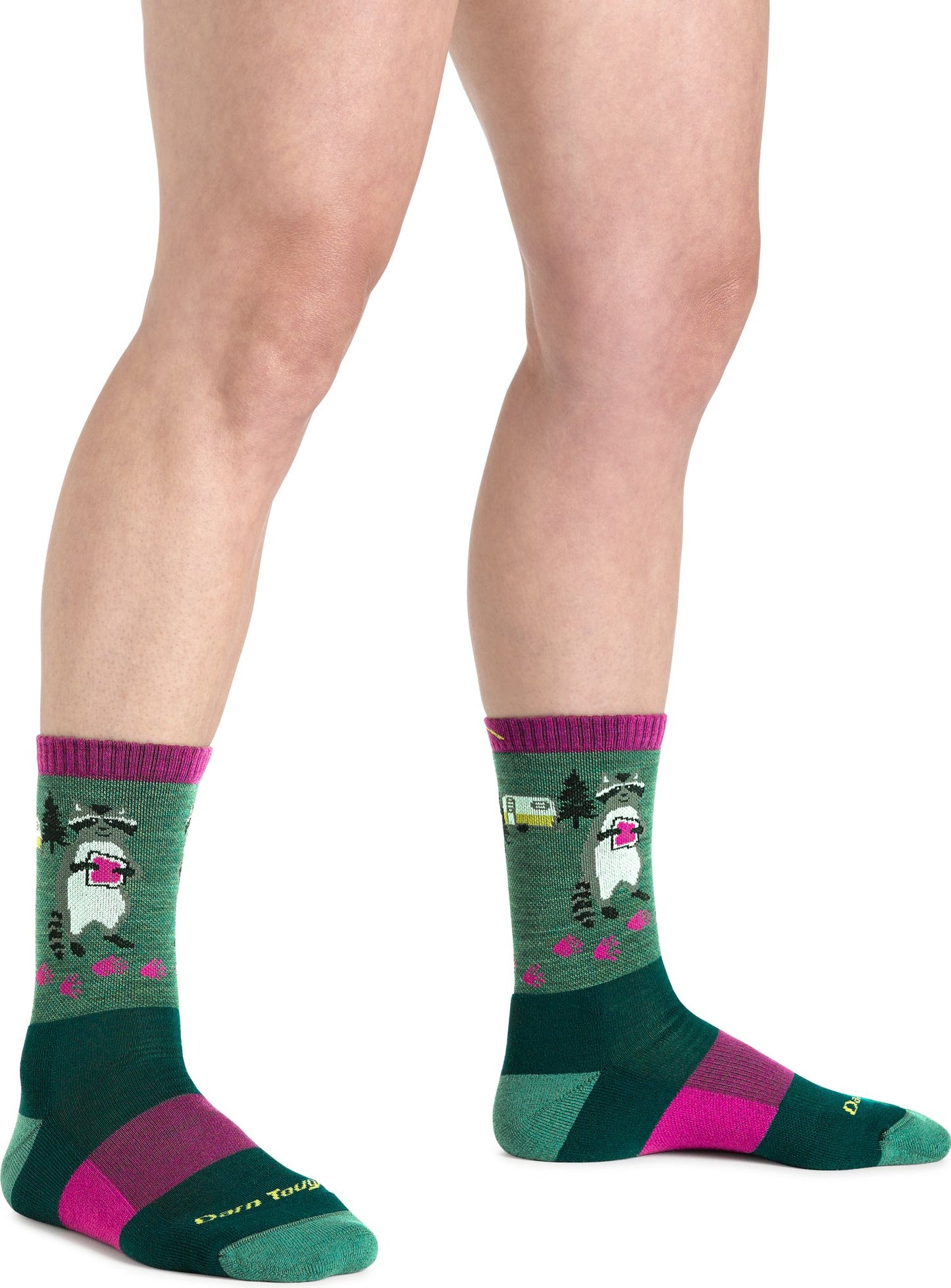 A person wearing Darn Tough green socks with a raccoon image and pink stripes.
