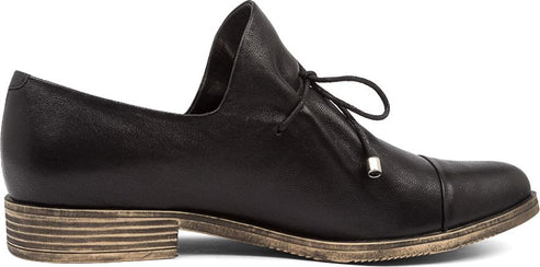 A black leather flat shoe with a tie closure.