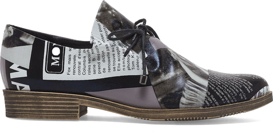 A black and white oxford shoe with the upper having a newspaper print with a flat heel and black laces.