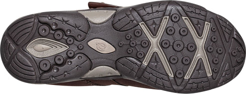 Bottom view of a shoe sole with circular and X-shaped treads in brown and gray.