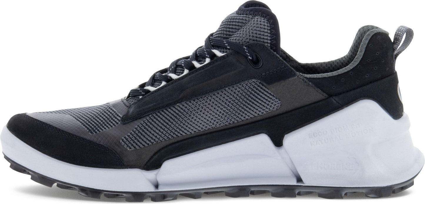 A low-rise athletic shoe with a black-and-grey upper and a thick white midsole.