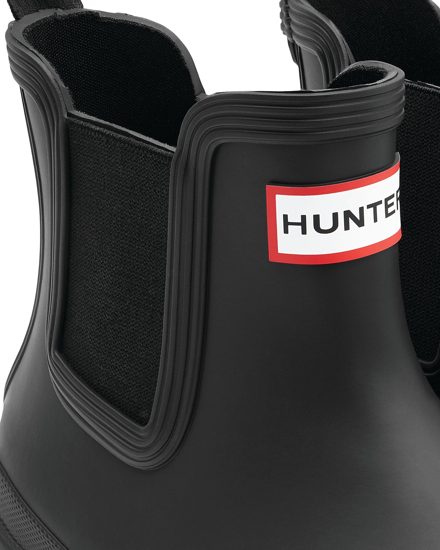 Close-up of a black Chelsea boot with HUNTER printed on a white and red label.