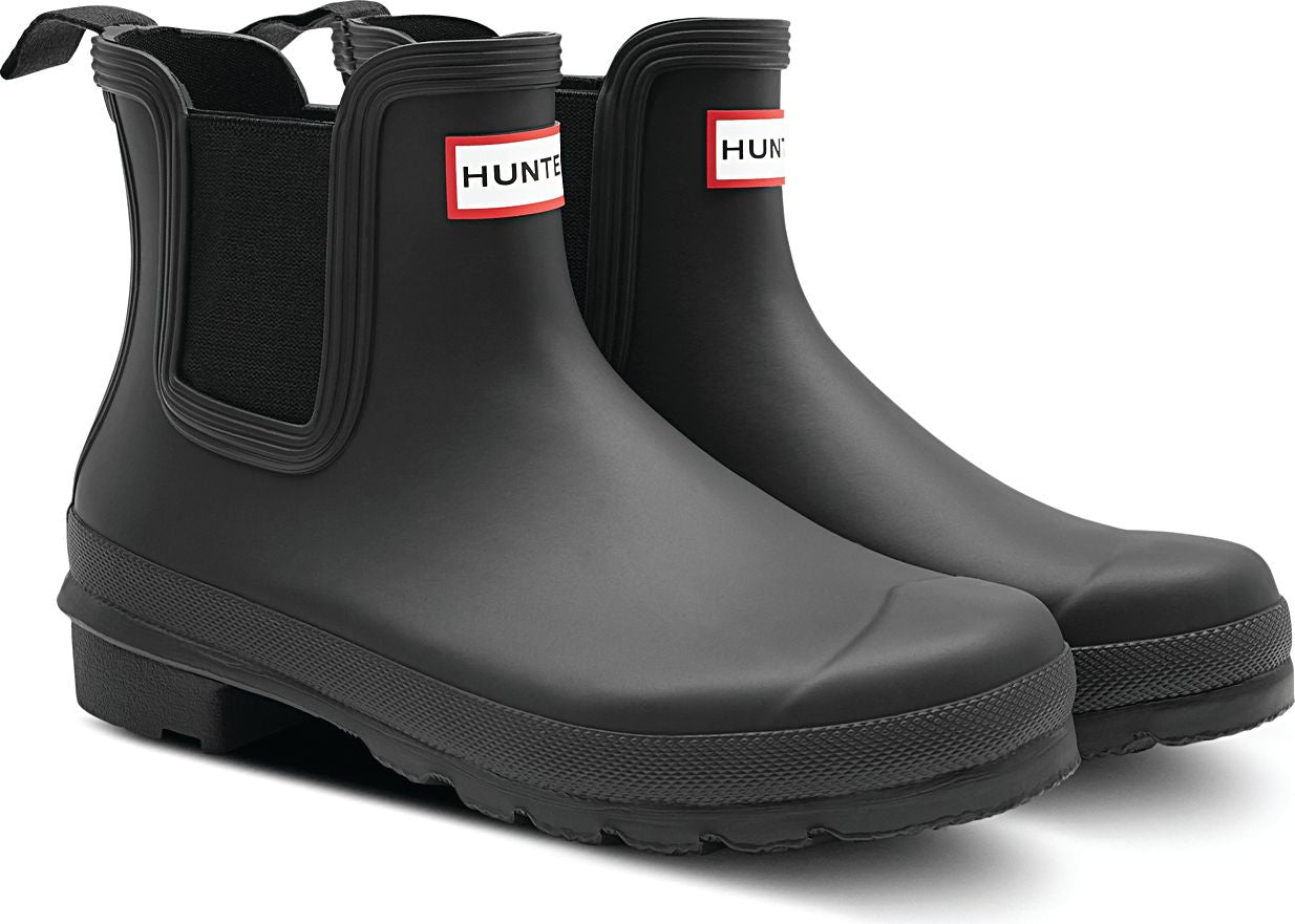 Two matte black rubber Chelsea boots with elastic side panels and red and white logo patches.