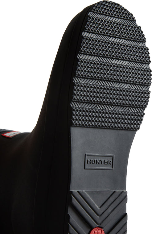 Close up of the black treaded rubber sole of a boot with a central logo.