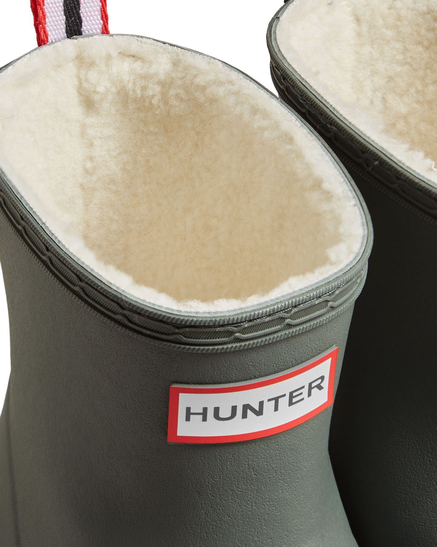 Close-up of a pair of olive-green rain boots with a white faux fur lining and a red-bordered tag that reads "HUNTER".
