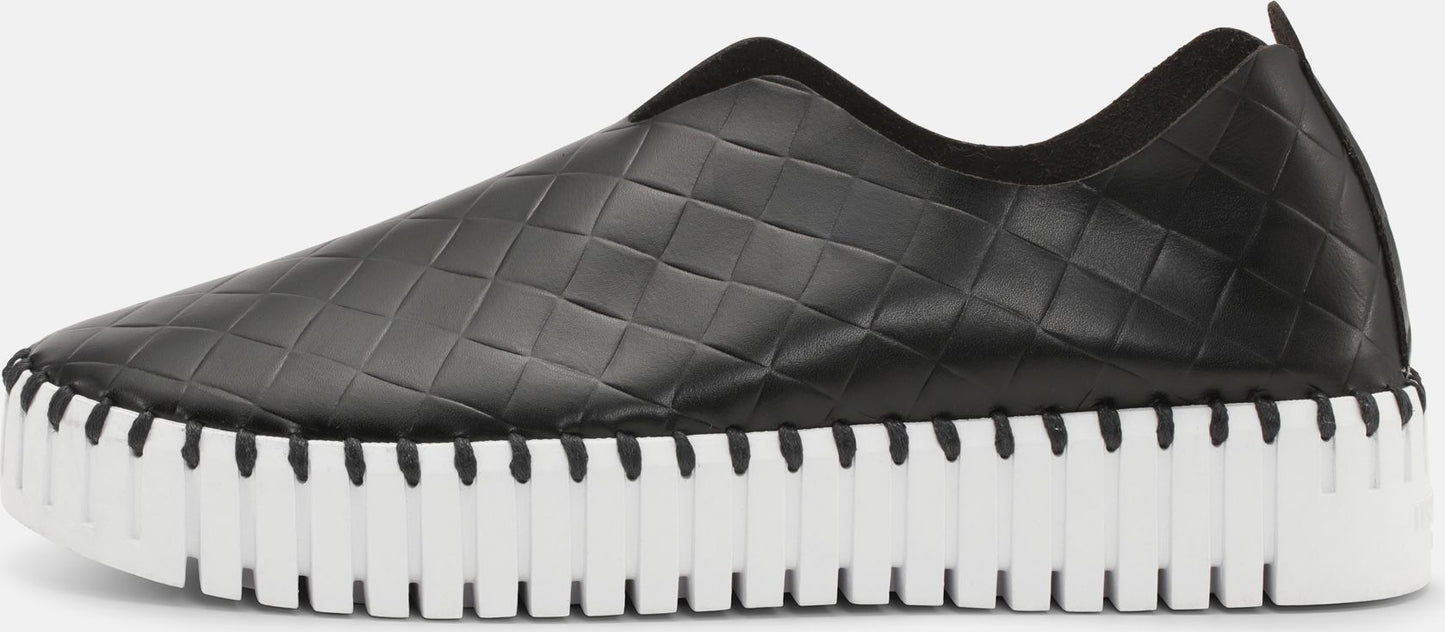 Black slip-on shoe with a white ridged sole.