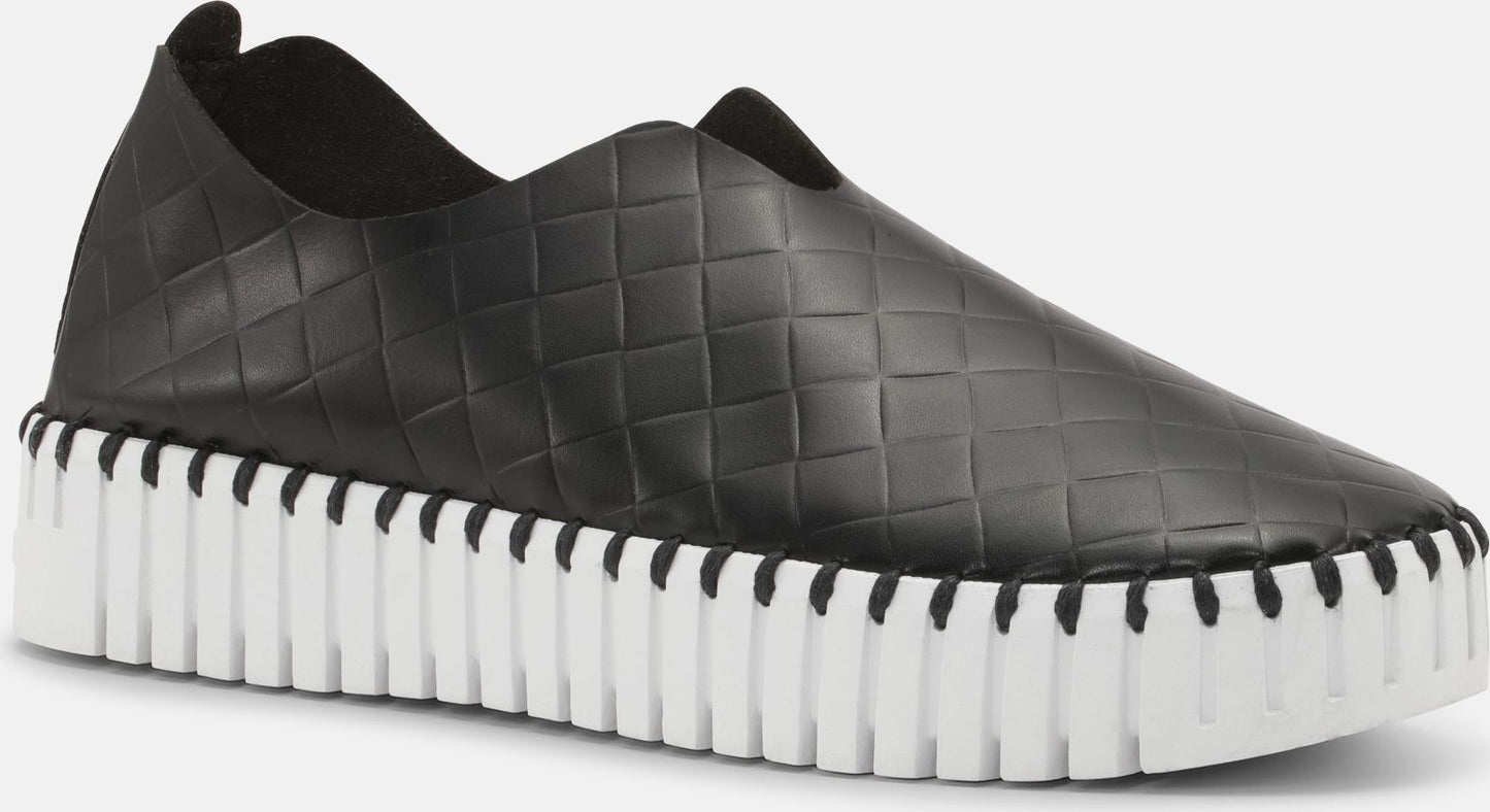 Black slip-on loafer with textured square pattern and thick white grooved sole.