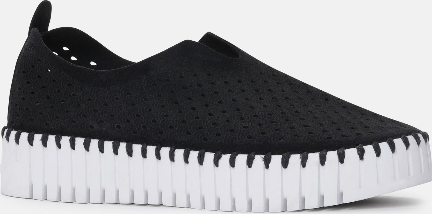 A black slip-on shoe with a thick white sole.
