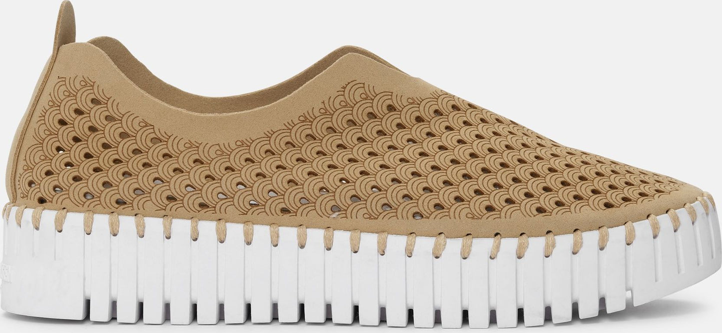 A tan slip-on shoe featuring a geometric pattern on the upper and a segmented white sole.
