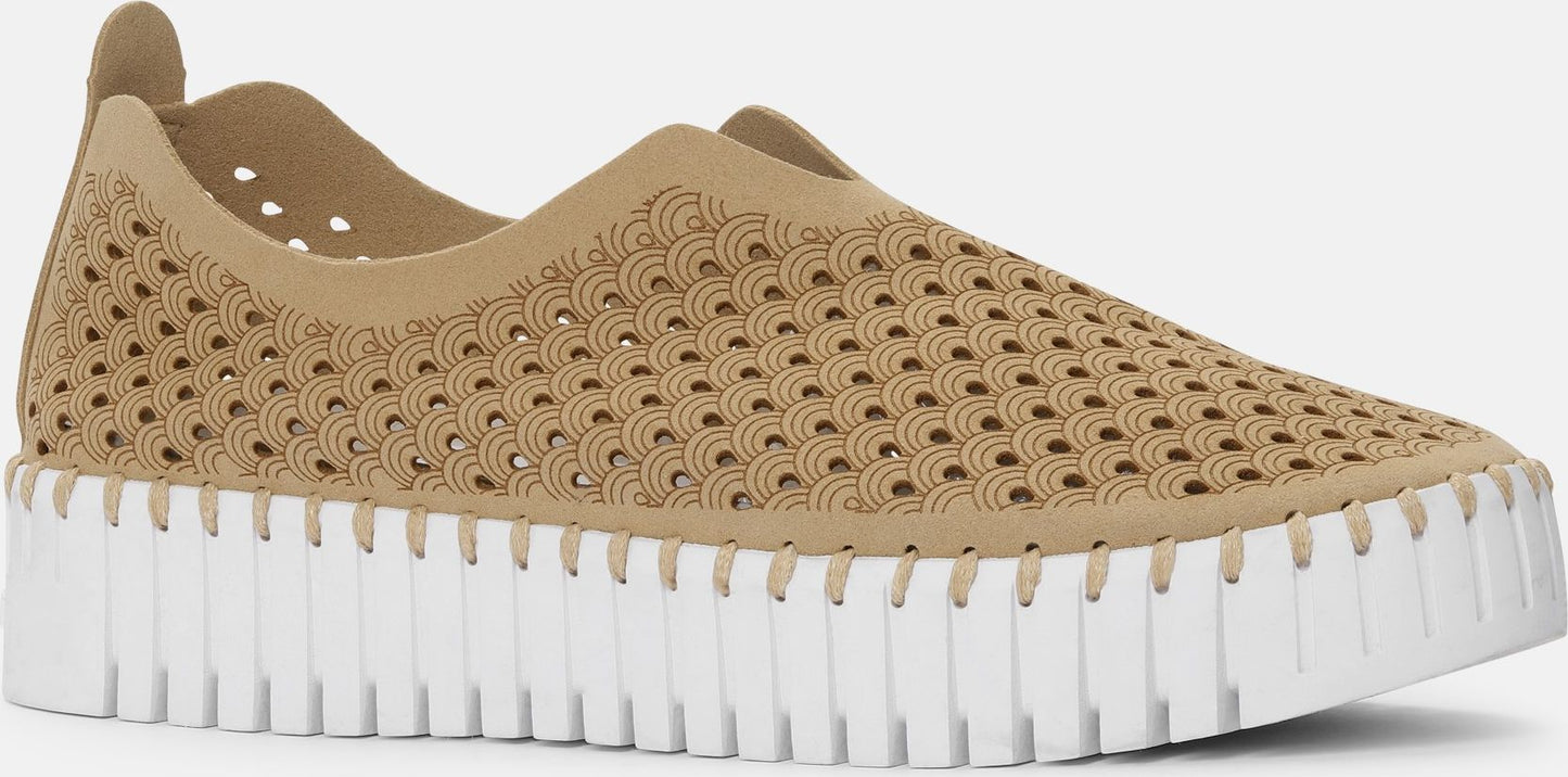 Beige slip-on shoe with decorative holes and a thick white sole.