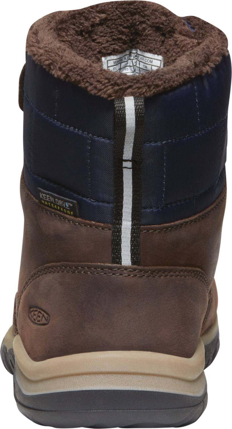 Back view of a waterproof brown leather boot with navy fabric, a velcro strap, and a brown faux fur trim.