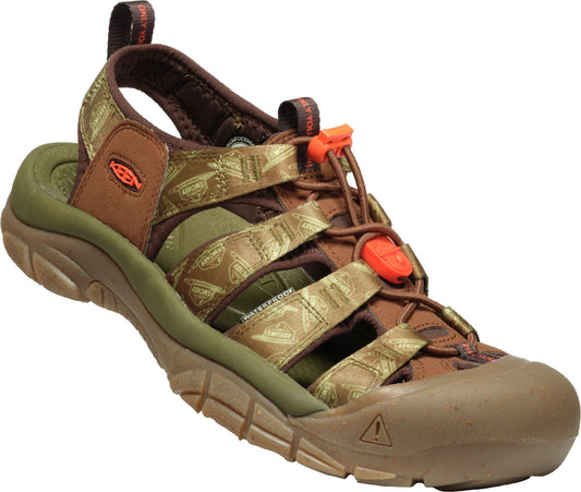 Angled view of a brown sandal with a green sole and orange toggle laces.