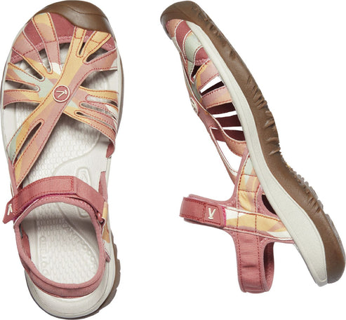 Two KEEN sandals, one viewed top-down and the other in profile, featuring interwoven pink, orange, and cream-colored straps over a white footbed and a pink ankle strap.