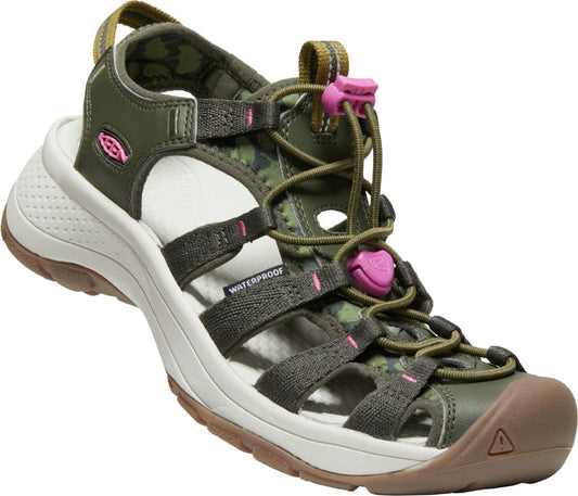 A dark green sandal with pink details and a beige sole. The sandal has multiple straps crossing the foot and a drawstring closure with pink toggles.