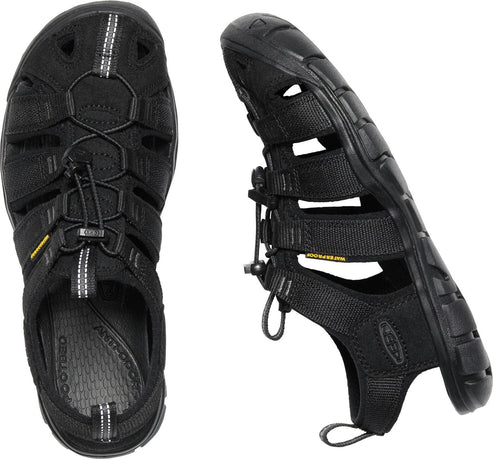 A pair of black sandals with an intricate webbing design and bungee cord lacing.