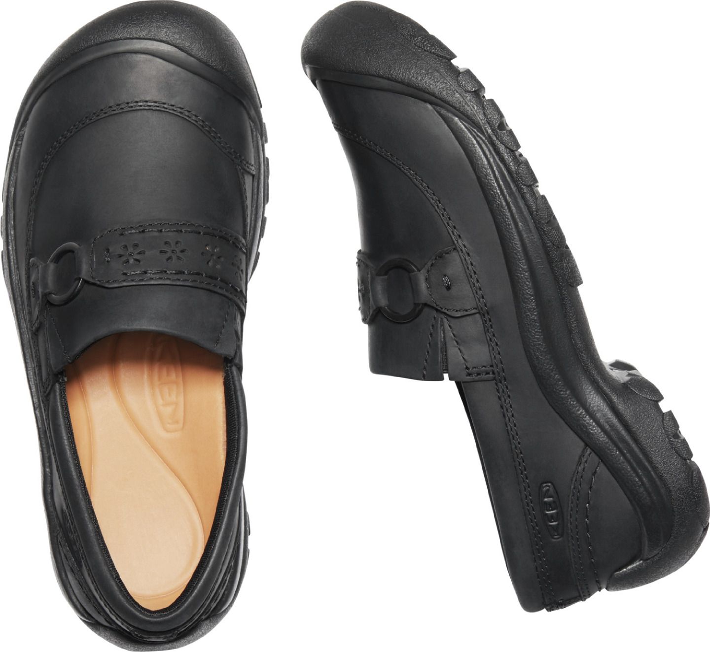 Two black, flat shoes, viewed from above and the side, show the style of a loafer and have decorative cutouts on the top.