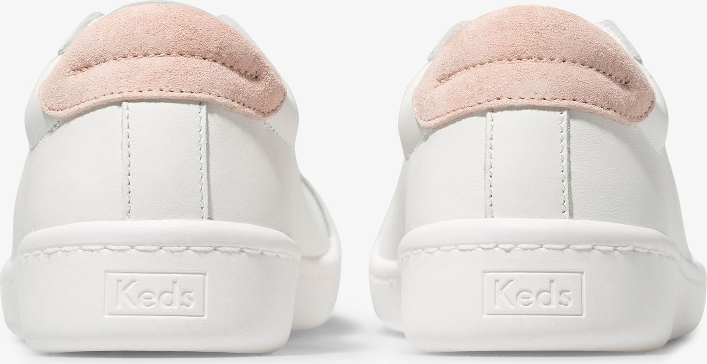 Back view of white sneakers with 'Keds' embossed on the heel and pink suede heel tabs.