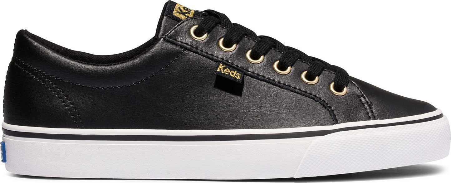 A black low-top sneaker with black laces, gold eyelets, and a white sole.