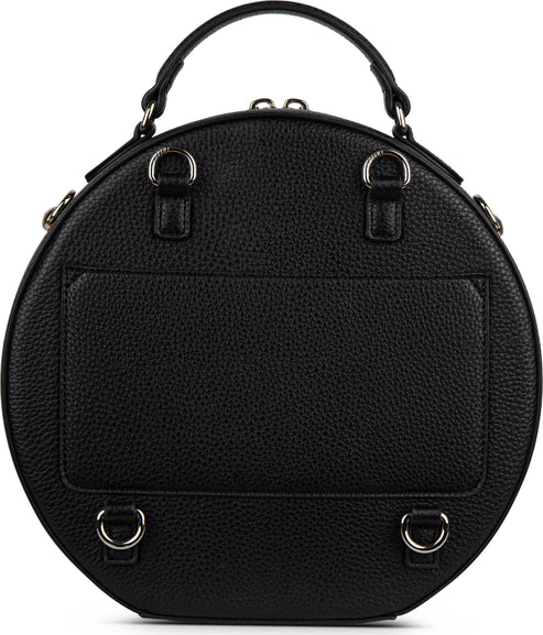 Back view of a black round satchel with a handle, a pocket, and metal hardware.