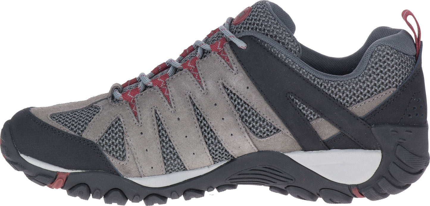 A side view of a gray and black trail shoe with red accents.