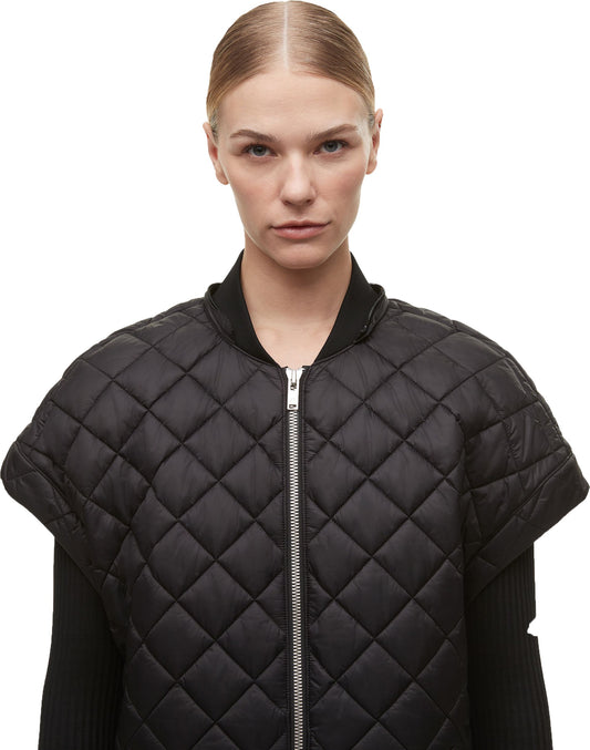 A person wearing a black quilted vest with a full zipper and short sleeves.