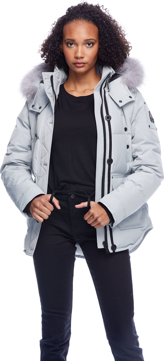 A woman wearing a gray fur-trimmed puffer jacket and black pants.