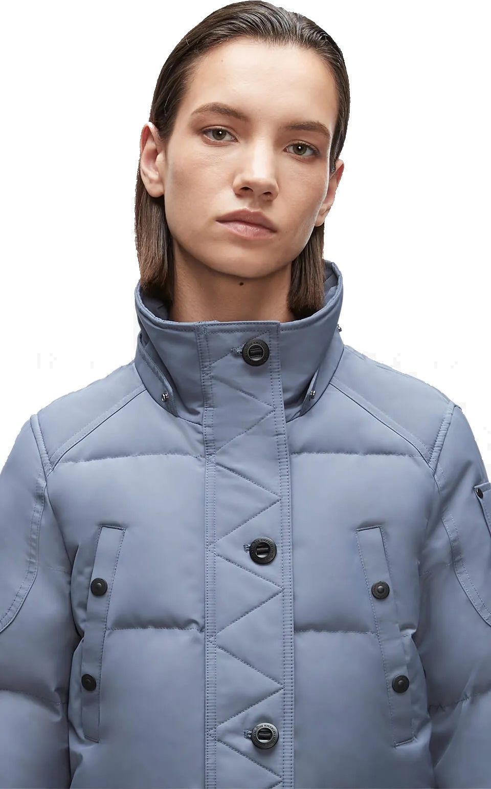 A woman wears a light blue puffer jacket with a buttoned high collar and button details on the front.