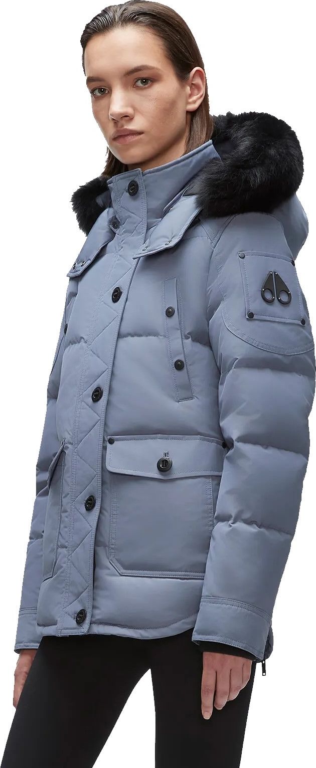 A woman wearing a blue puffer coat with black fur around the hood.